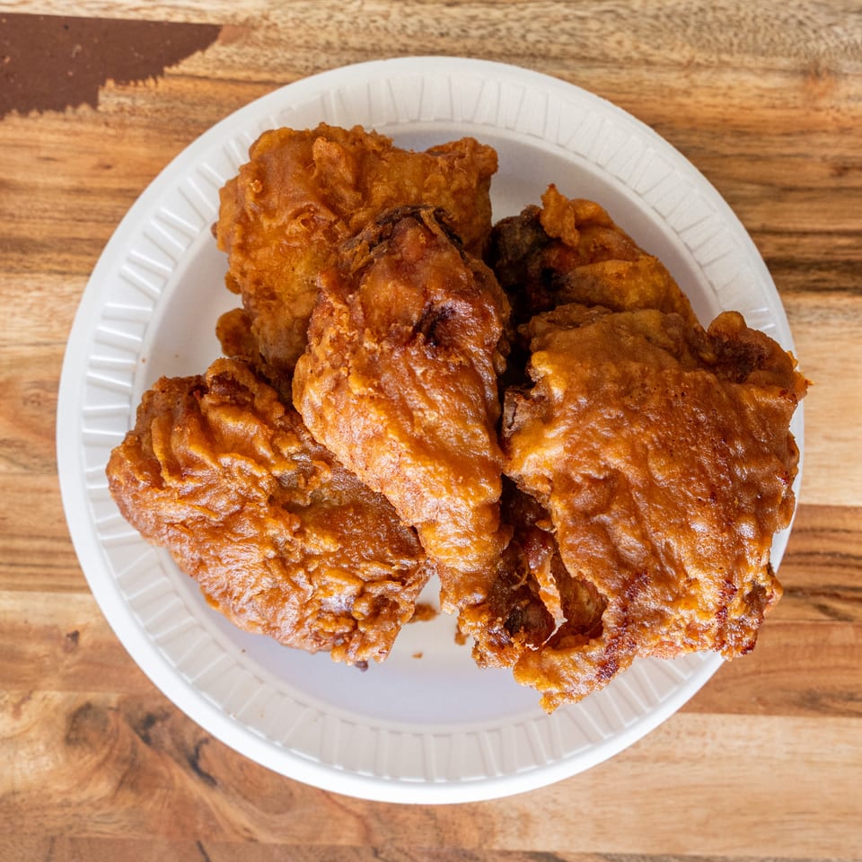 A white plate piled with golden-brown pieces of crispy fried food sits on a rustic wooden table.